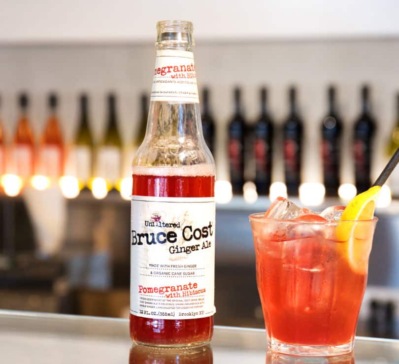 Photo of a cocktail in a glass next to a small bottle of ginger ale